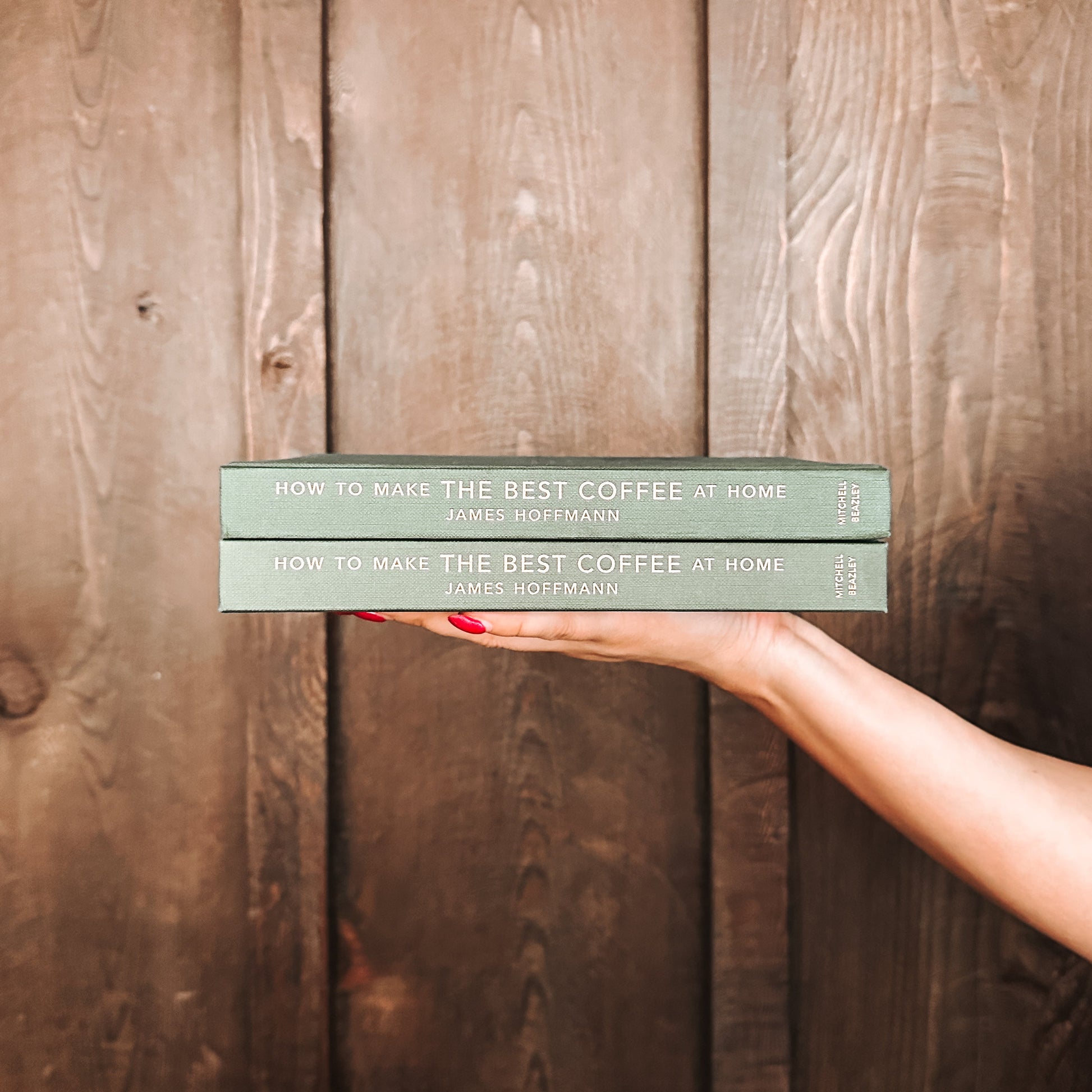 Two books titled 'How to Make the Best Coffee at Home' held against a wooden background